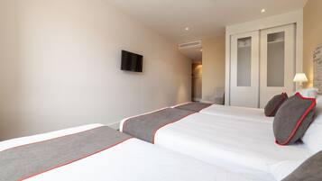 Ett hotellrum med två sängar, en tv som är monterad på väggen och en skjutdörrsgarderob.
