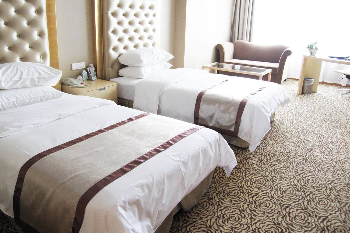A hotel room with two beds, a sofa, a desk, and a chair.