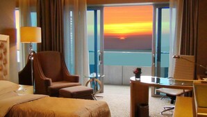 A hotel room with a bed, a desk, a chair, and a view of the sunset over the water. - Glarun Jinling Hotel Nanjing (Nanjing)