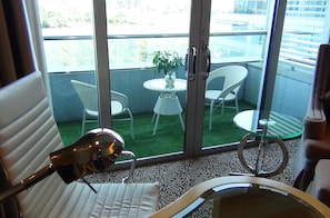 A room with a bed, a chair, a table with a plant, and a balcony with chairs and a table. - Glarun Jinling Hotel Nanjing (Nanjing)