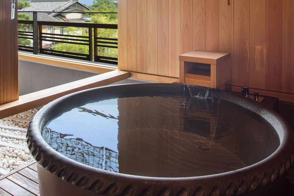 A hot spring bath with a wooden bench and a small wooden cabinet.