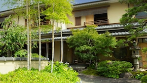 A traditional Japanese building with a tiled roof, a stone lantern, and lush greenery. - Ryotei Rangetsu (Kyoto)