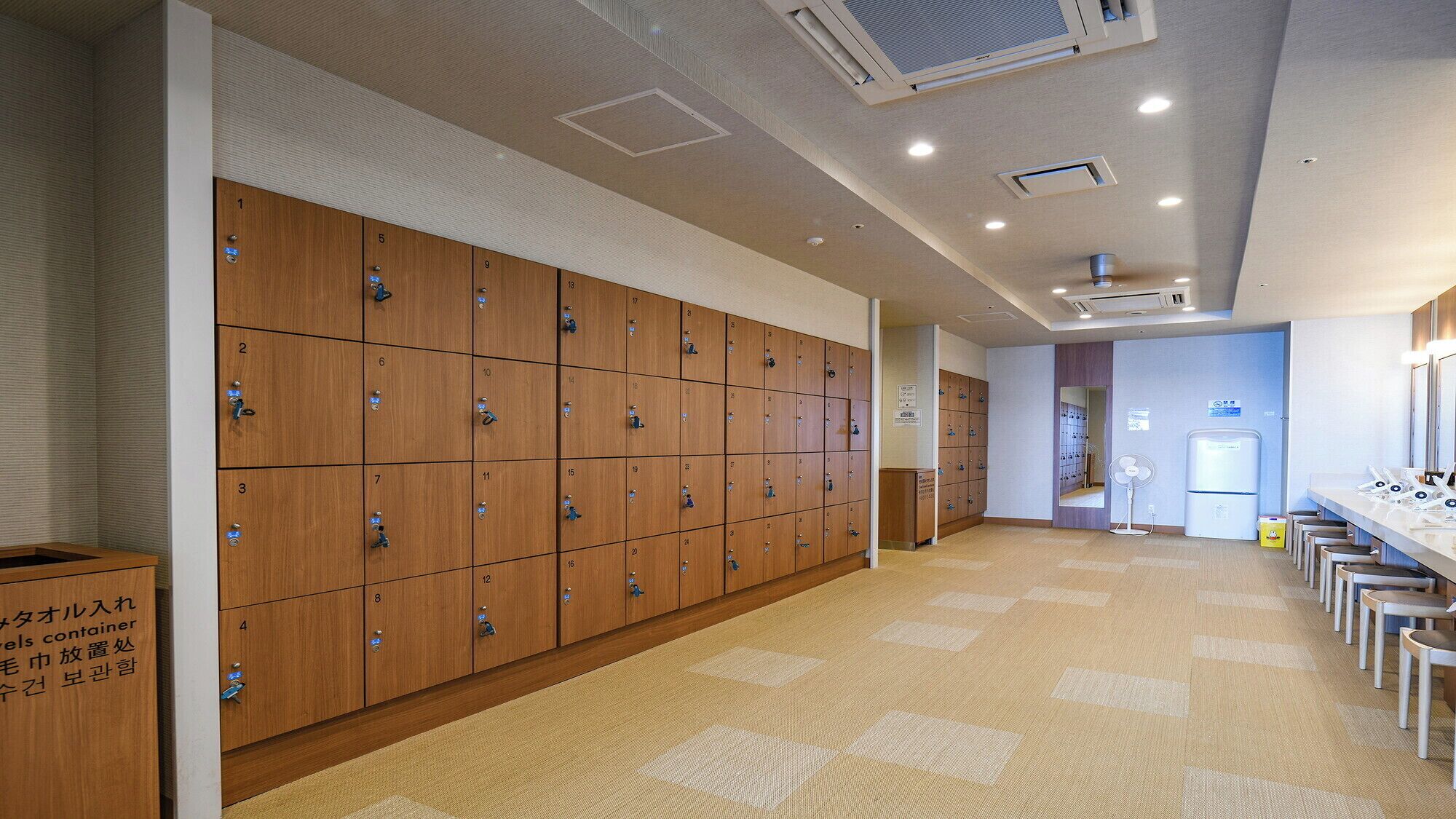 A hotel bathroom with wooden lockers, a sink area, and a mirror.
