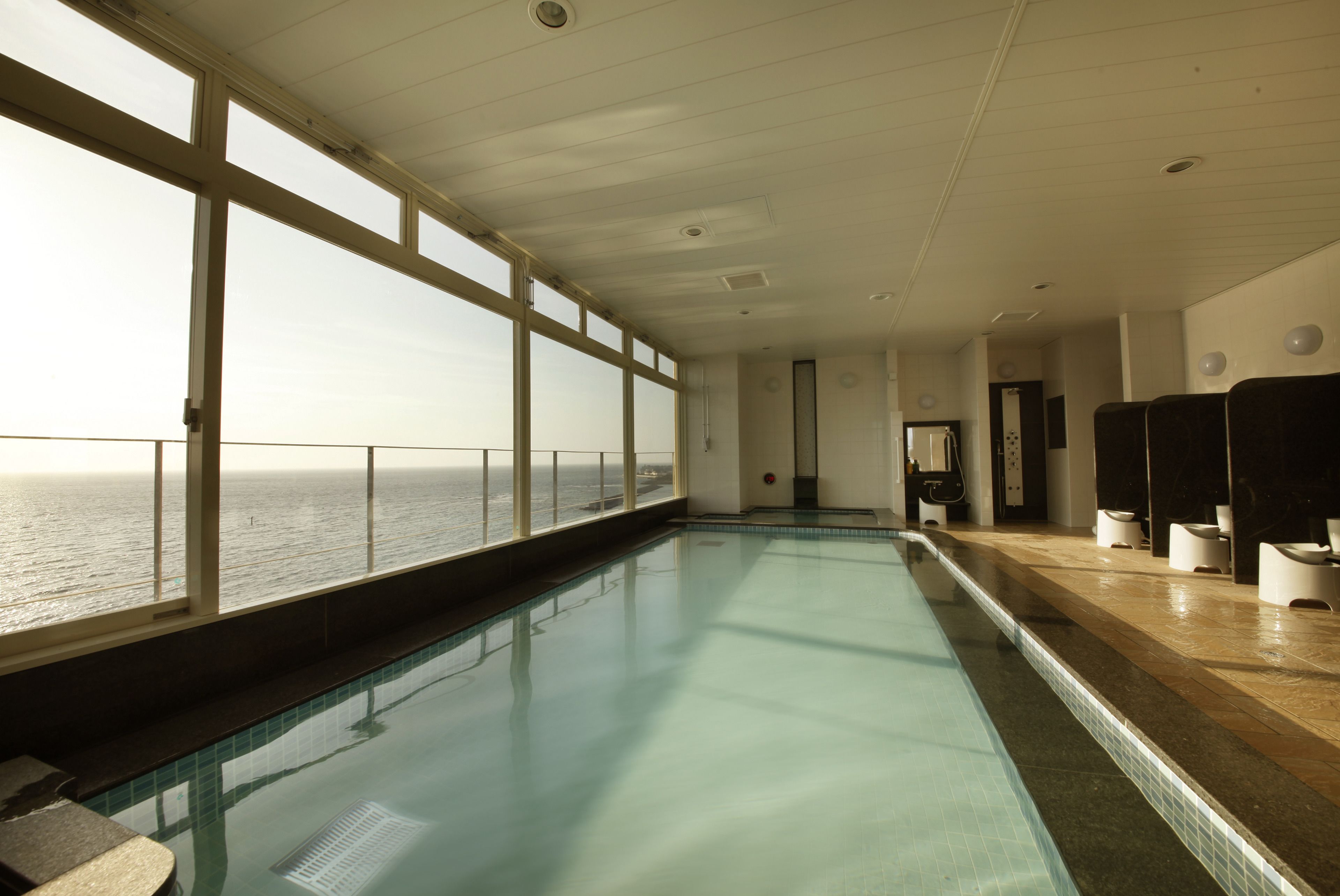 Una piscina amb vistes al mar, una zona de vestidors i un paviment de rajoles.