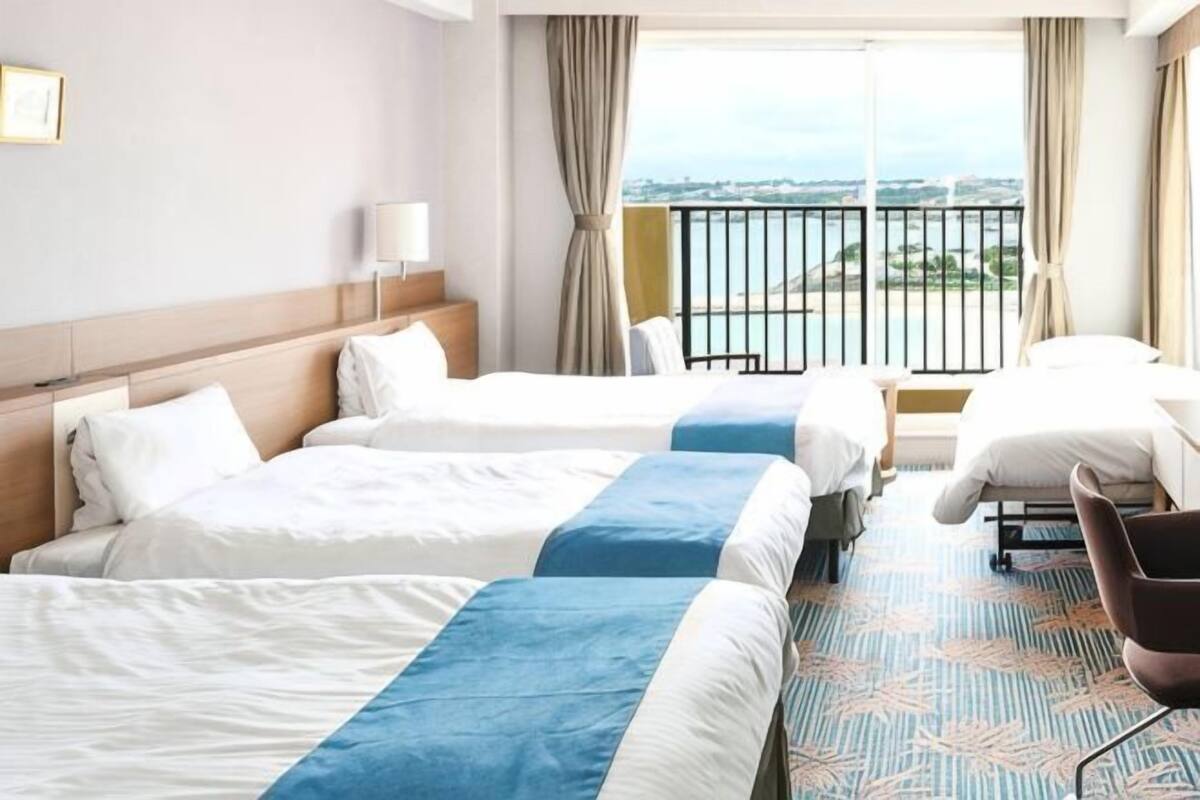 Une chambre d’hôtel avec deux lits, une vue sur la mer et un balcon.