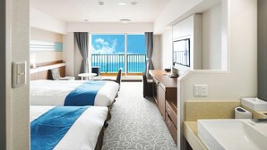 Een hotelkamer met twee bedden, een bureau, een stoel, een televisie en een balkon met uitzicht op zee.