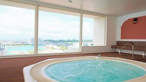 Ruime kamer met groot raam en uitzicht op de stad, een jacuzzi en een houten vloer.