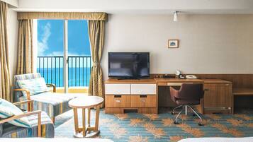 Una habitación de hotel con balcón, televisión, escritorio y una silla.