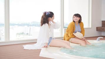Two people sitting by a hot tub with a city view.