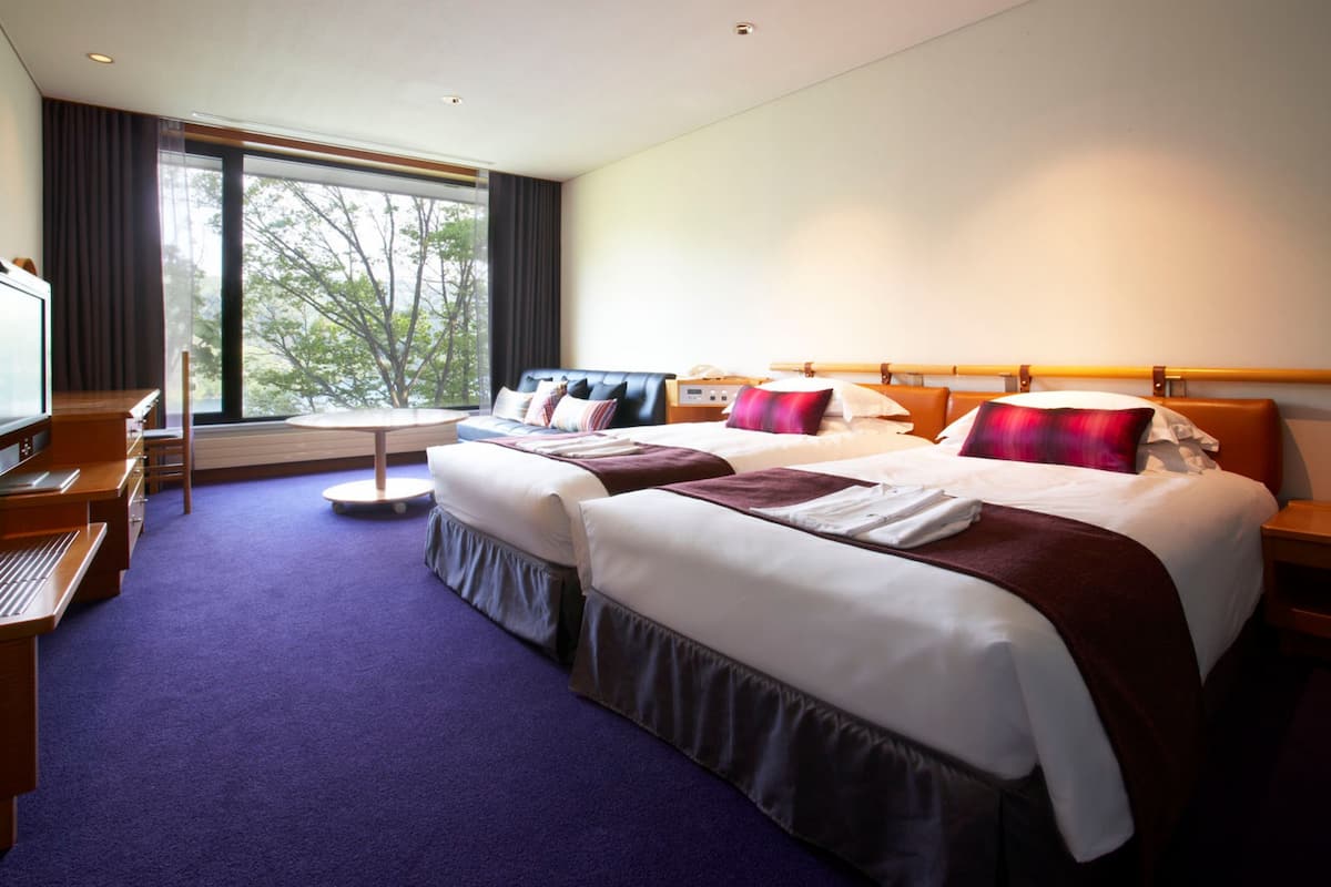 Een hotelkamer met twee bedden, een bureau en een televisie.