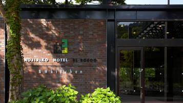 The exterior of the Nojiriko Hotel El Bosco with a brick facade and a glass entrance.