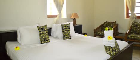 Una habitación de hotel con una cama bien hecha, una silla, una lámpara y cortinas.