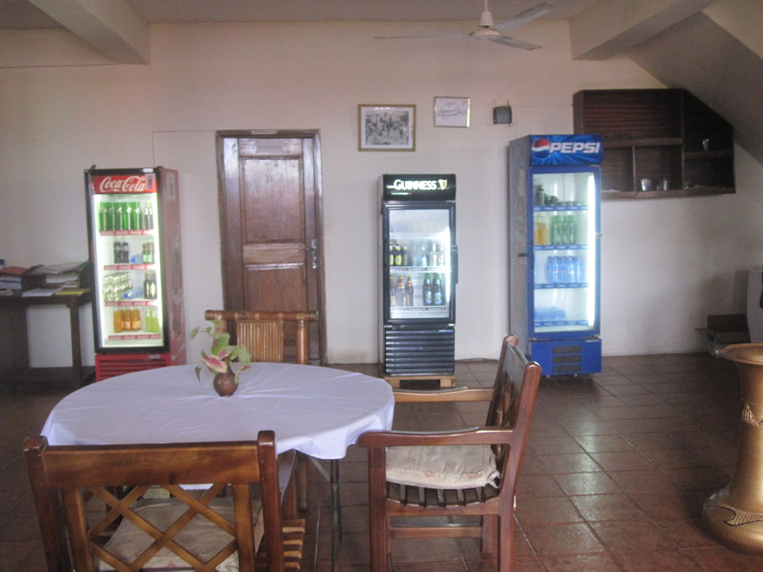 Un comedor con una mesa y sillas, un refrigerador con bebidas y una puerta.