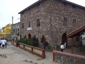 A stone building with arched windows and a signboard. - Coconut Grove Bridge House (Elmina)