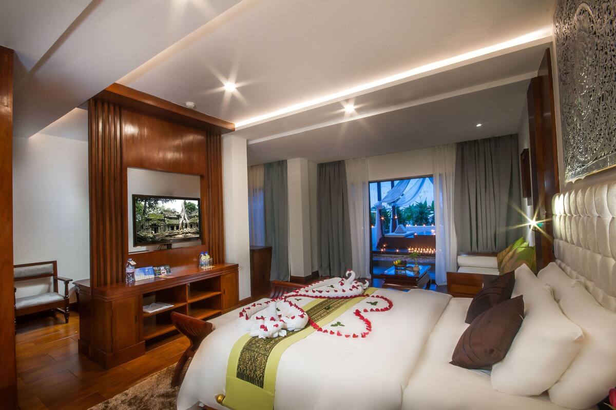 Ein geräumiges Hotelzimmer mit einem großen Bett, einem Fernseher und Blick ins Freie.