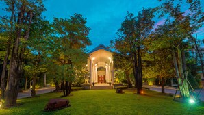 A well-lit building with a central entrance, surrounded by trees and a lawn. - THE PRIVILEGE FLOOR by Borei Angkor (Siem Reap)