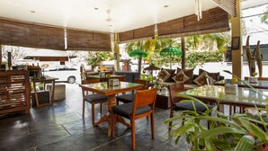 A spacious indoor area with a large table and chairs, a sofa, and various plants. - Berawa Beach Residence (Tibubeneng)