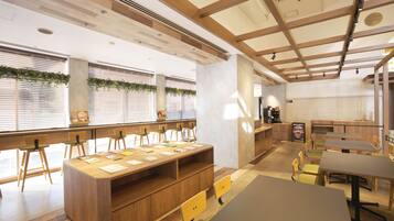 A modern meeting room with wooden tables, chairs, and a long table with papers.