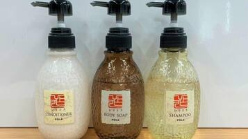 Tres botellas de productos de cuidado personal con dosificadores, etiquetadas como acondicionador, jabón corporal y champú, todas con la marca 'POLA'.