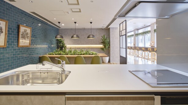 Une cuisine moderne dotée d’un évier en acier inoxydable, d’un four encastré et d’un coin repas avec une longue table et des chaises.