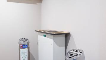 Habitación de hotel con aire acondicionado blanco, un escritorio con una computadora portátil y dos botes de basura.