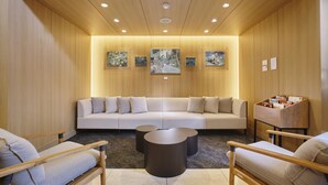 Un salon moderne avec un canapé, deux fauteuils, une table basse et des œuvres d’art accrochées aux murs.