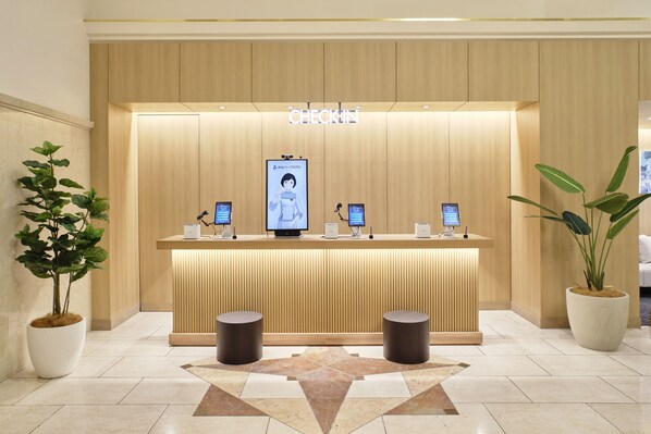 A reception desk with a 'CHECK-IN' sign, two monitors, a digital screen, and potted plants. - Takamatsu Park Hotel (Takamatsu)