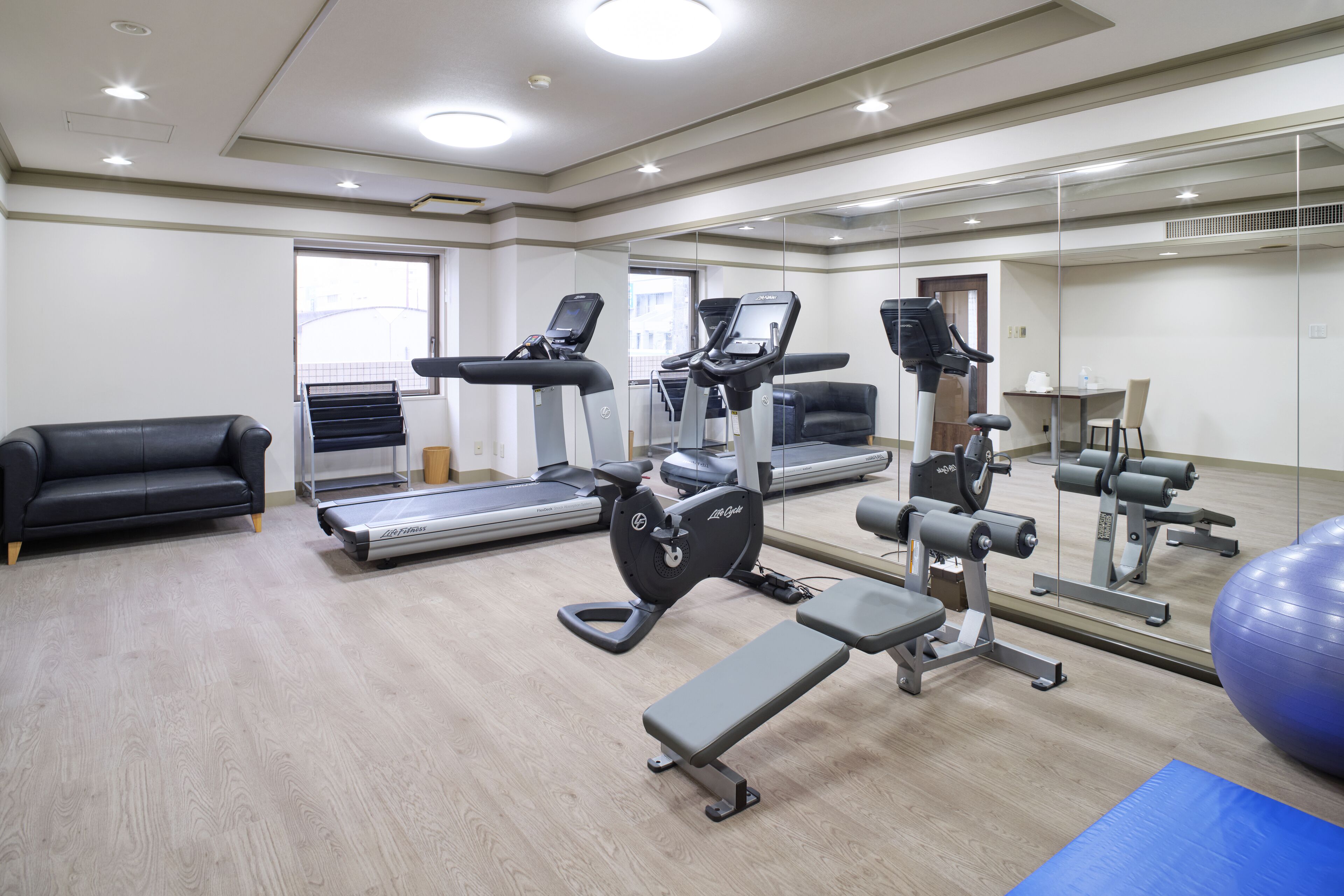 A gym with treadmills, exercise bikes, and a bench.
