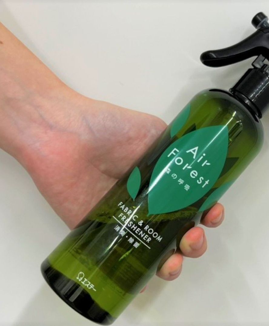 A hand holding a bottle of Air Forest fabric & room freshener.
