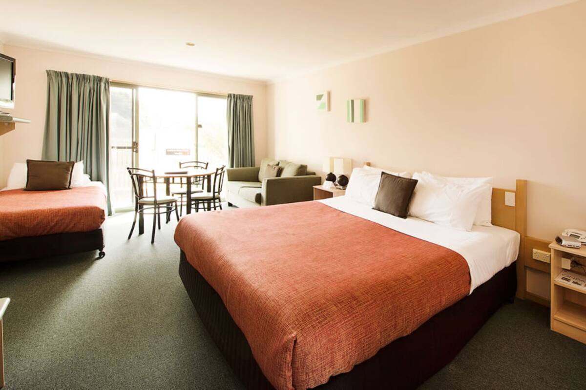 A hotel room with two beds, a dining area, and a TV.
