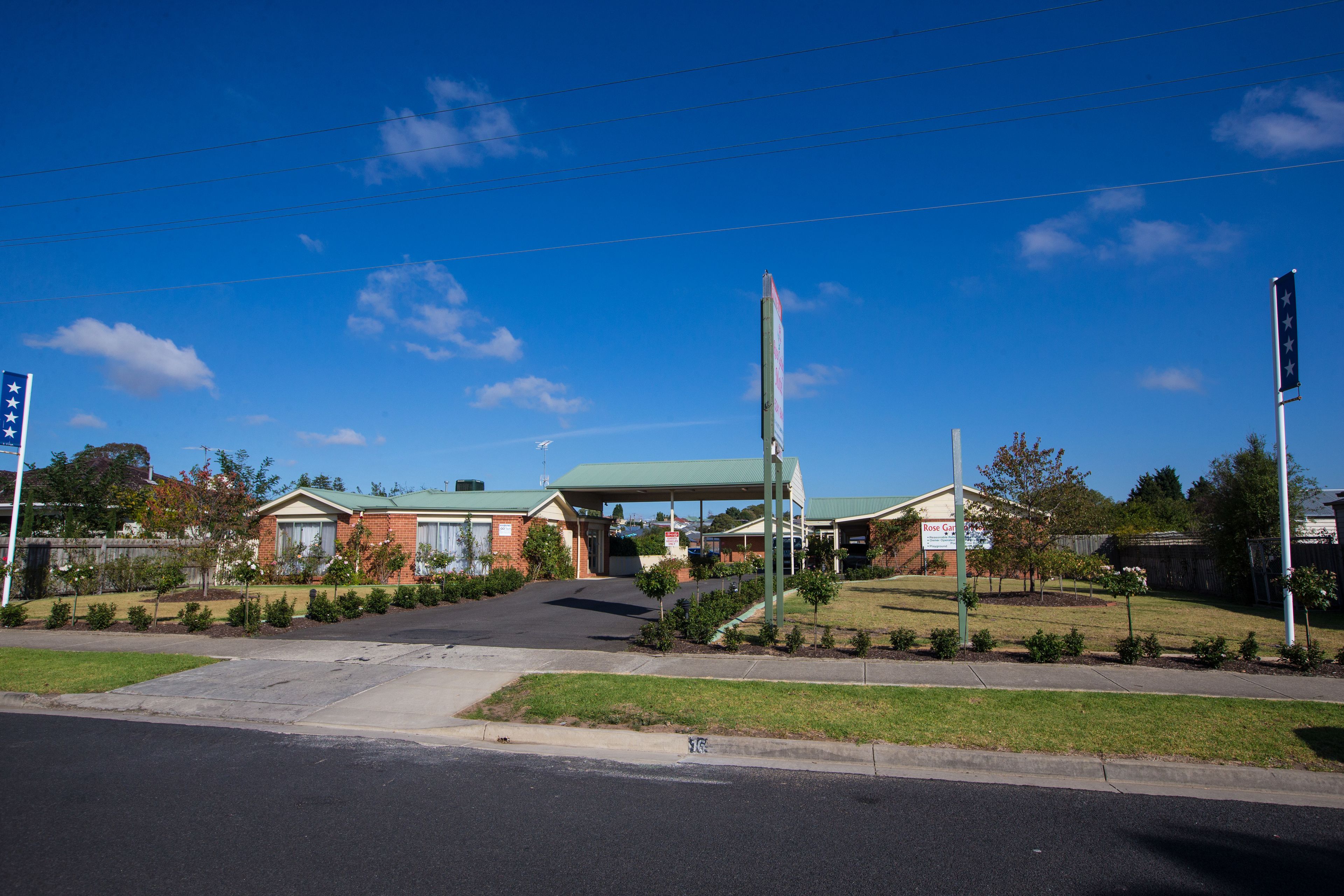 A commercial building with a green roof, a parking lot, and a clear blue sky.