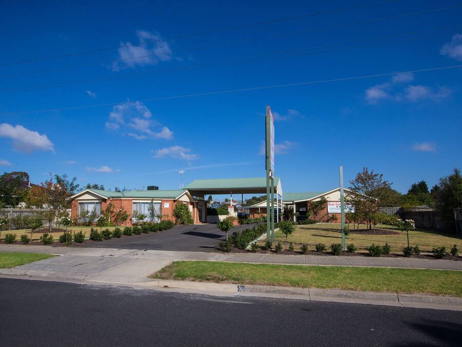 A commercial building with a green roof, a parking lot, and a clear blue sky.