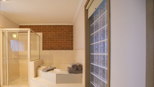 Un baño con cabina de ducha de vidrio, bañera y pared de azulejos.