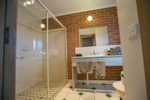 Un baño con cabina de ducha de vidrio, lavabo con espejo y retrete.