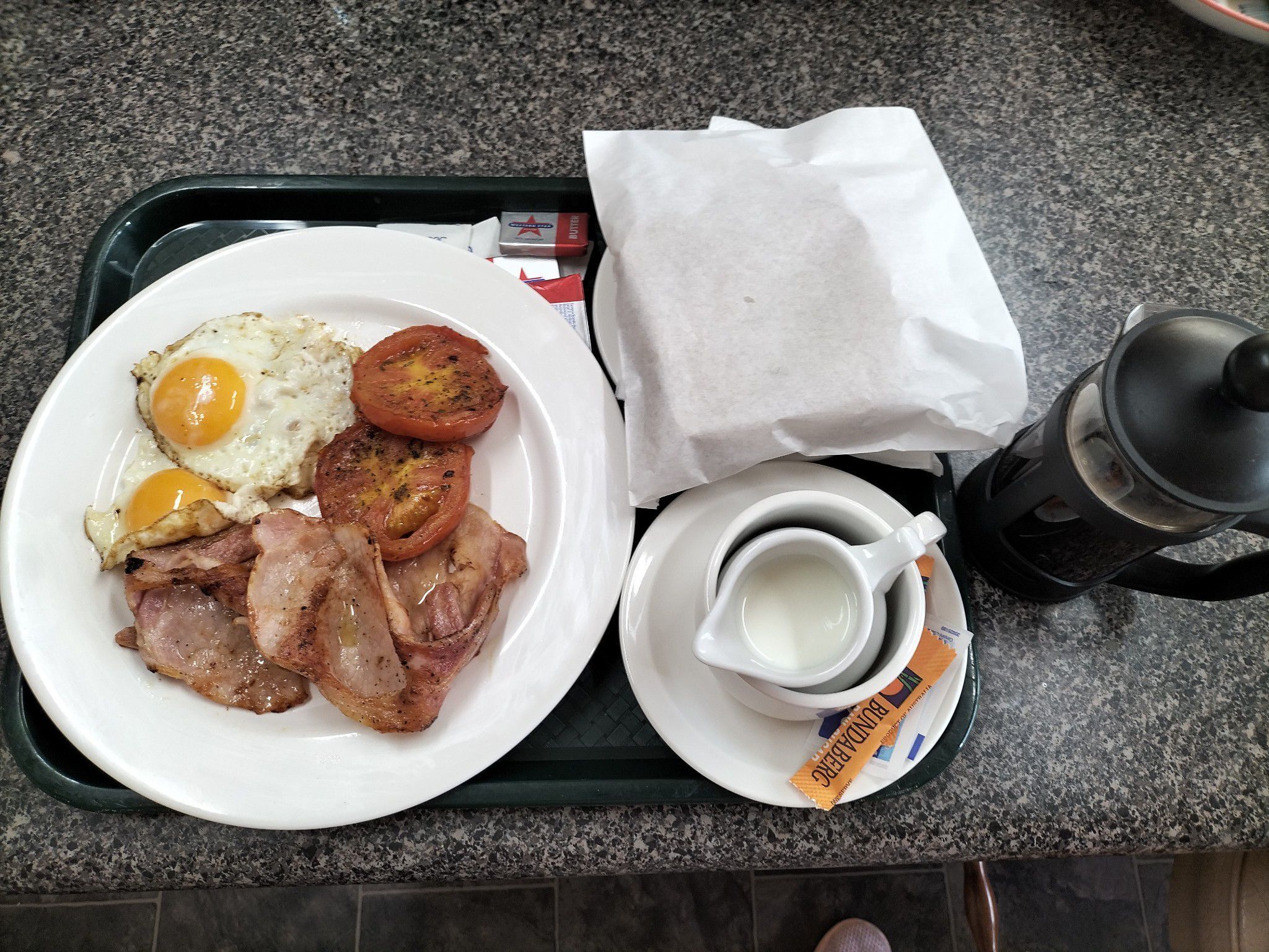 Bandeja de desayuno con huevos, tocino, tomates y una taza de café.