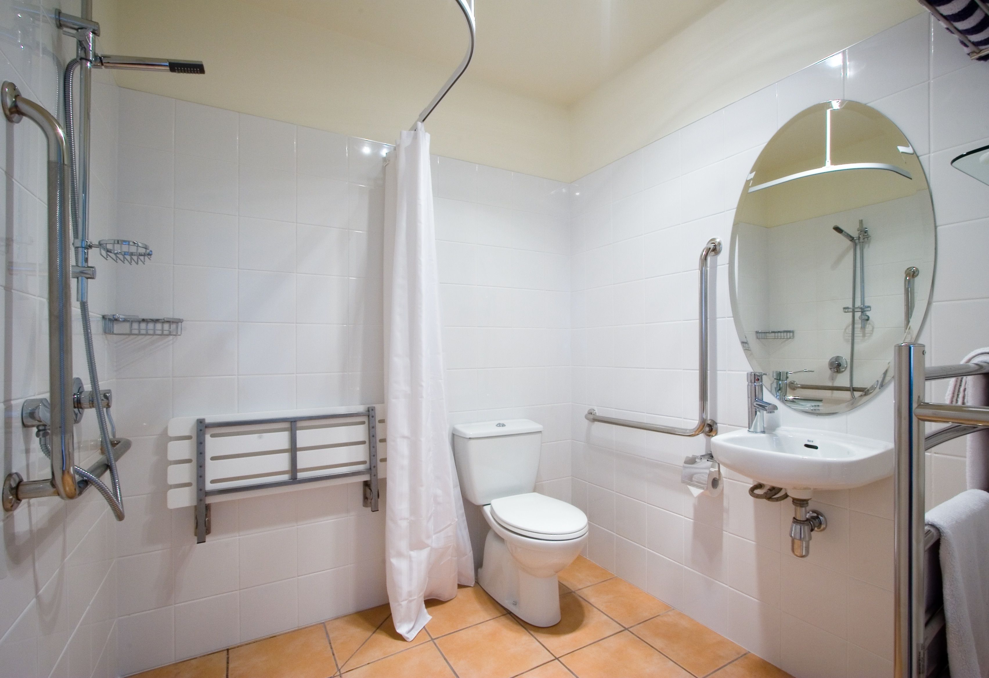 A bathroom with a shower, toilet, sink, and a mirror.