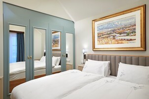 Habitación de hotel con una cama grande, un espejo, un cuadro y vistas a las montañas.