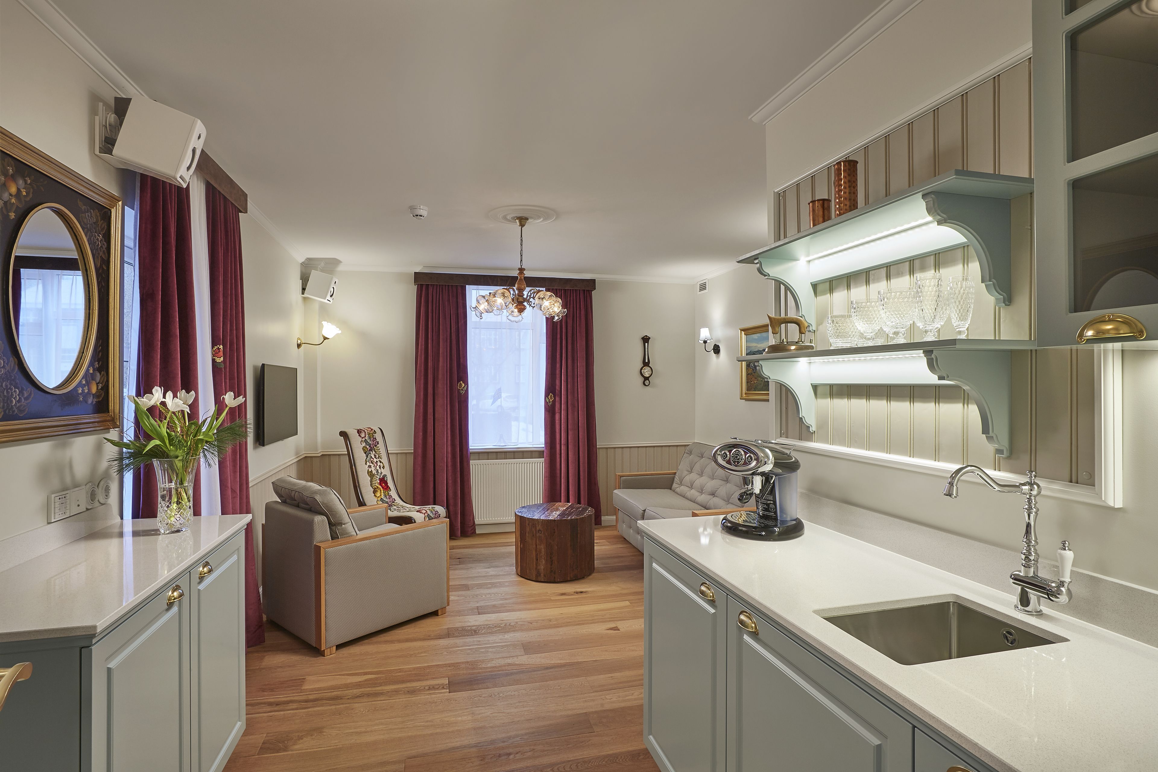 A modern kitchen with a built-in sink, a dining area with a sofa, and a large window with curtains.