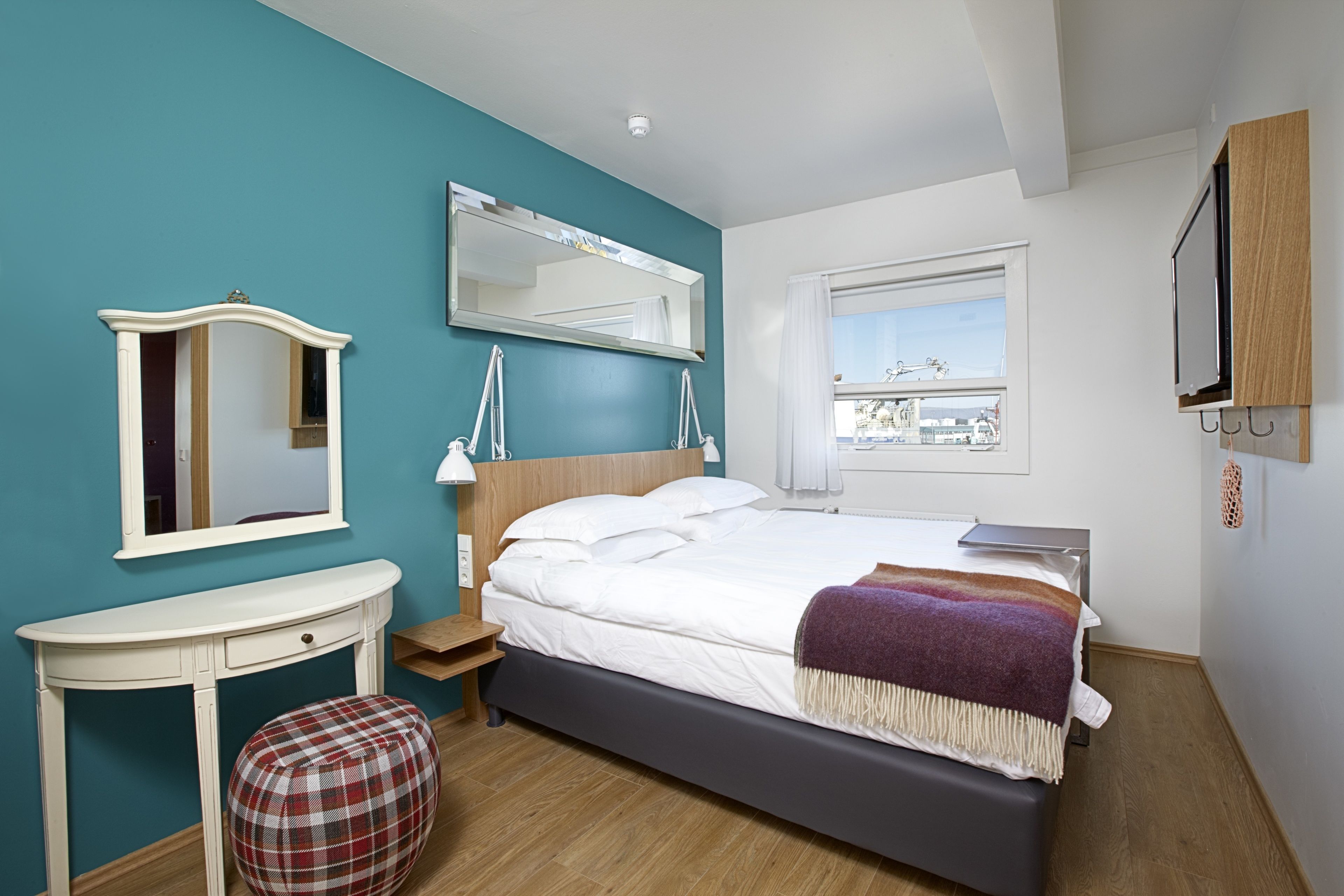 Une chambre à coucher avec un lit, une table de chevet, une chaise, un miroir et une fenêtre.