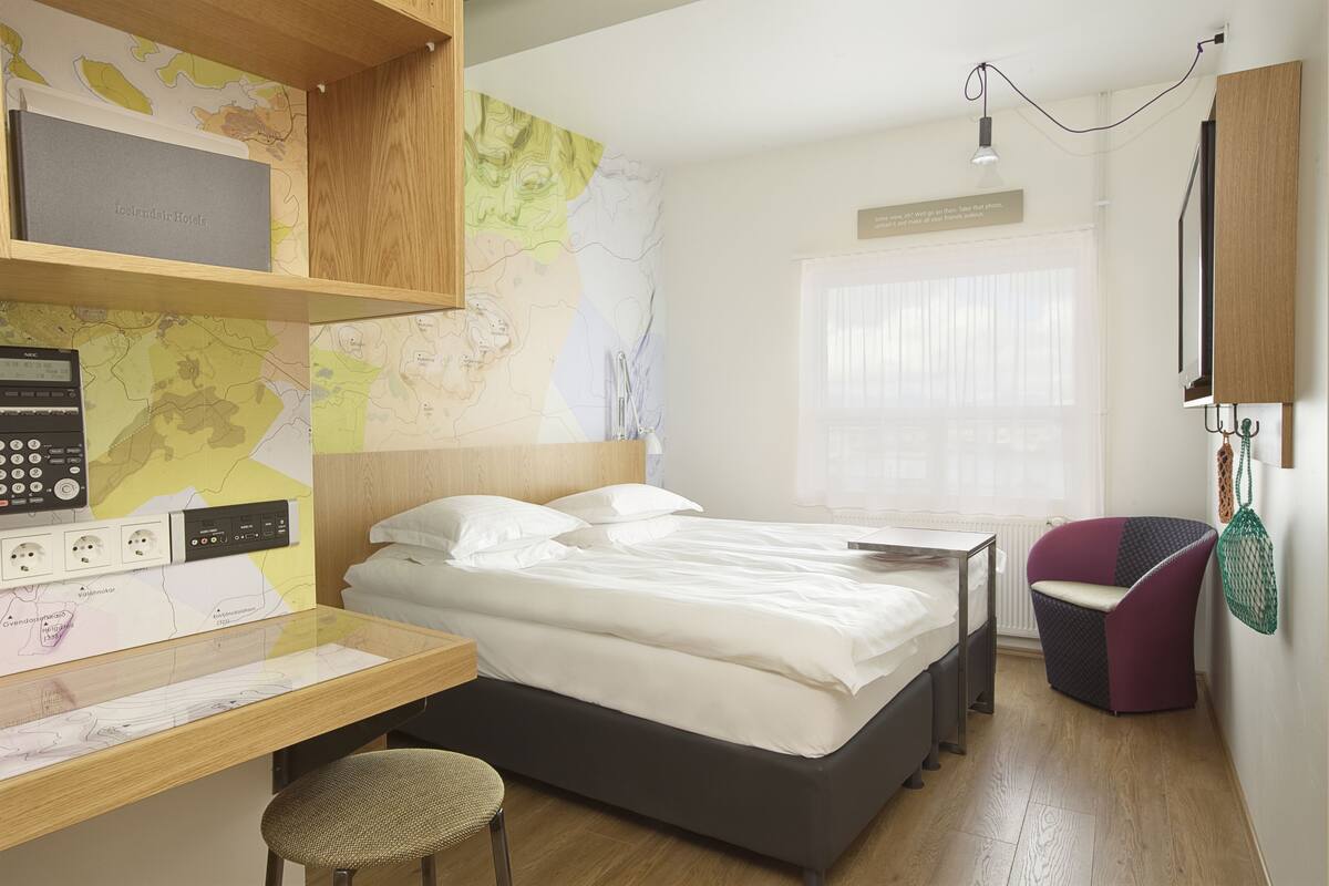 Een moderne hotelkamer met een bed, bureau, stoel en een kaart aan de muur.