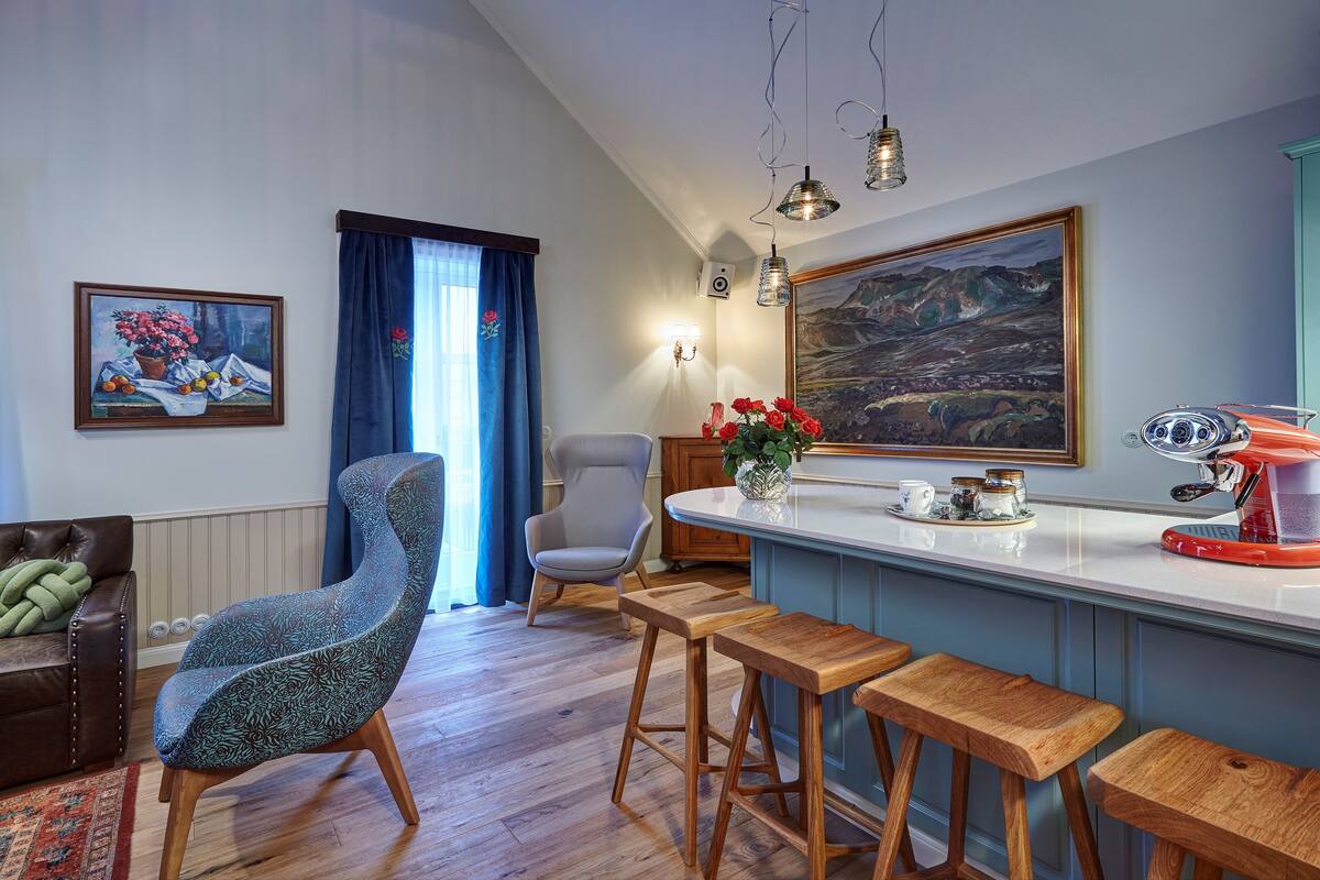 Een moderne keuken met een bar, houten krukken, een kinderstoel en een schilderij aan de muur.