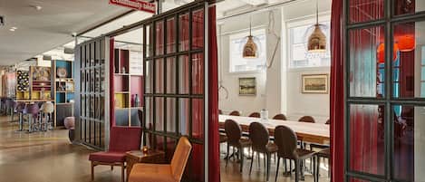 A spacious room with a long table and chairs, a red chair, and a bookshelf with various items.