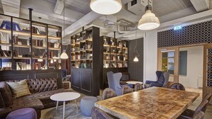 Uma biblioteca moderna com estantes, um sofá de couro, uma mesa de madeira e assentos confortáveis.