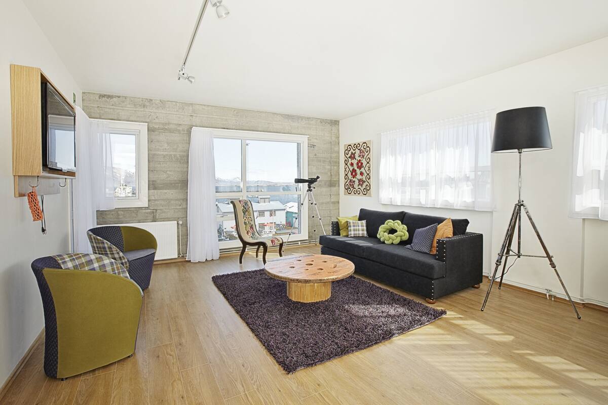 Een moderne woonkamer met een bank, fauteuils, een salontafel en een vloerlamp.
