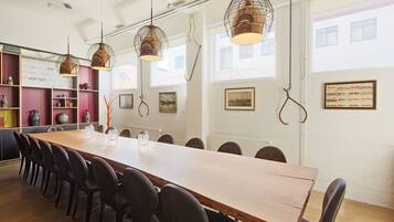 A long wooden table with chairs, pendant lights, and shelves with decorative items.
