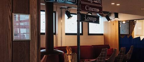 A lobby with directional signs to various facilities such as restrooms, elevators, stairs, a cinema, lounge, and a slippin' bar.