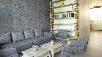 A modern lounge area with a grey textured wall, a sofa, and patterned chairs.