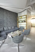 A modern lounge area with a grey textured wall, a sofa, and patterned chairs.