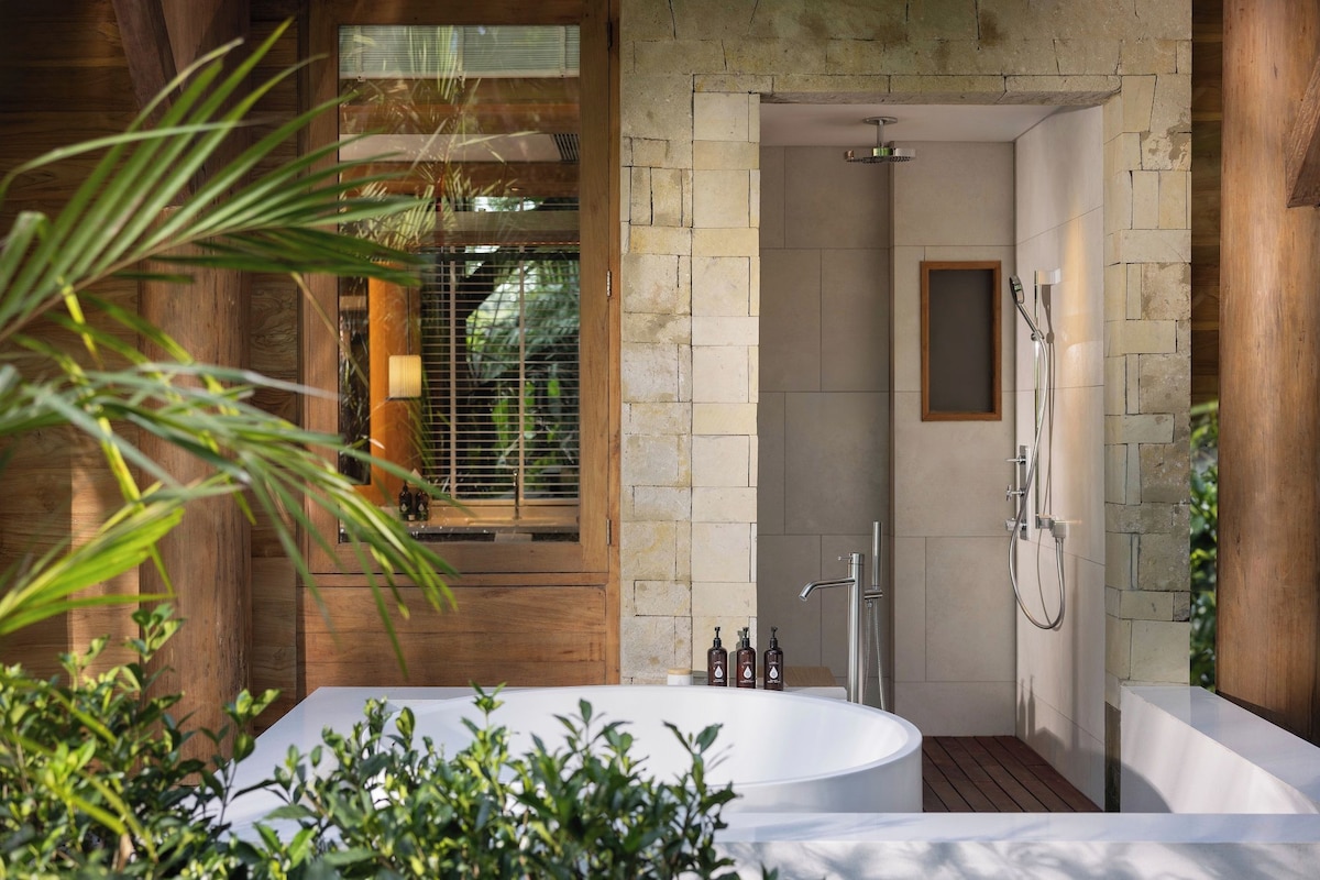 Un baño moderno con una bañera independiente, ducha y ventana con persianas.