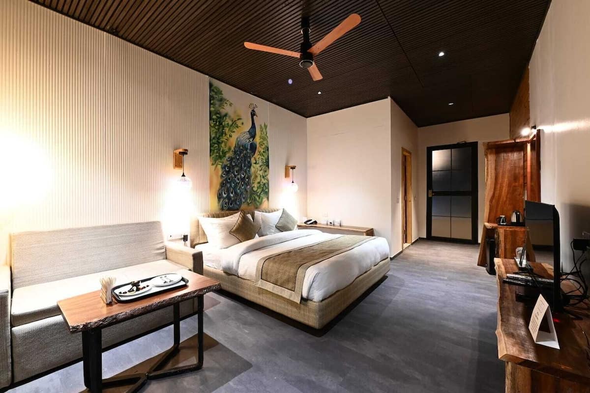 Una habitación de hotel moderna con una cama grande, un escritorio y un mural de un pavo real en la pared.